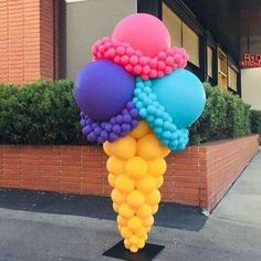 a bunch of balloons that are on top of a pole in front of a building