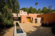 Peach earth tone palette modern home exterior with flagstone walkway, native landscaping & architectural pond water feature.