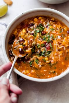 a person holding a spoon full of chili soup