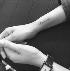 two hands holding each other with the word love tattooed on their wrist and another person's arm behind them