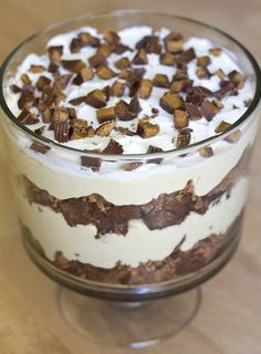 a dessert in a glass dish on a wooden table with white frosting and chocolate chips