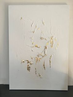 a white painting with gold paint on it