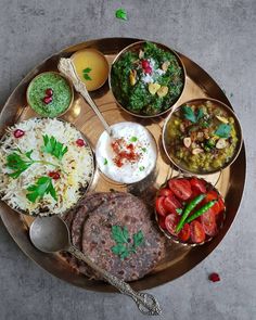 an assortment of food on a plate with spoons and utensils in it