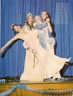 three women in dresses and tiaras posing for a photo on stage with one woman holding the other