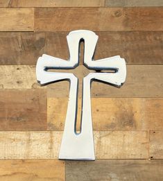 a white metal cross sitting on top of a wooden wall