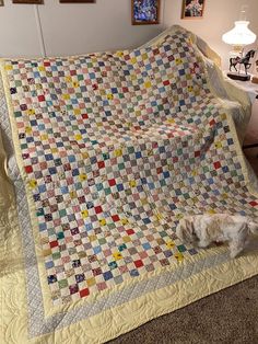 a bed with a quilt on top of it in a room next to a lamp