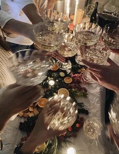 many people are holding wine glasses at a table