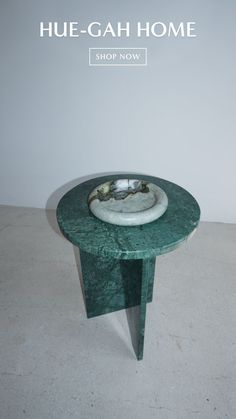 a green table with a white bowl on it and the words hue - cah home above it