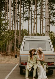 two women sitting next to each other in front of a van with trees behind them