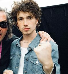 two men standing next to each other in front of a black background with one holding his arm around the other's shoulder