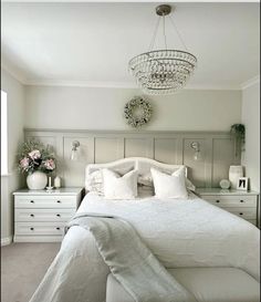 a white bed sitting under a chandelier in a bedroom