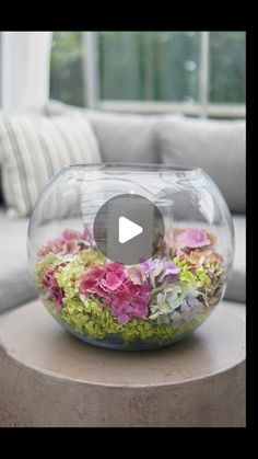 a glass bowl filled with flowers sitting on top of a table next to a couch