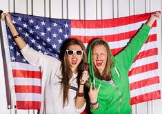 two young women standing in front of an american flag