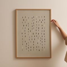 a person holding up a framed art piece with black and white lines drawn on it