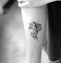 a small tattoo on the arm of a girl with an angel holding a bouquet of flowers