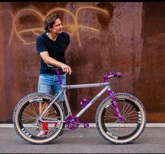 a man standing next to a bike with graffiti on it