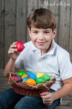 a young boy holding an easter basket with colored eggs in it