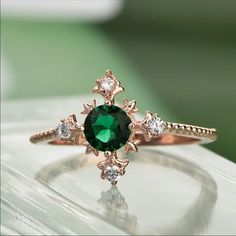 a close up of a ring with a green stone in the middle and white diamonds around it