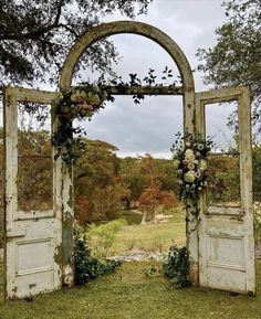 an old door is decorated with flowers and greenery in the middle of a field