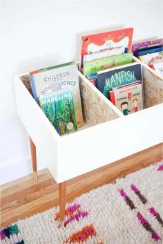 a white table with books in it and a rug on the floor