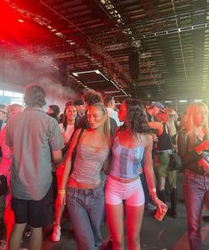 two women in short shorts and tank tops are walking through the crowd at a music festival