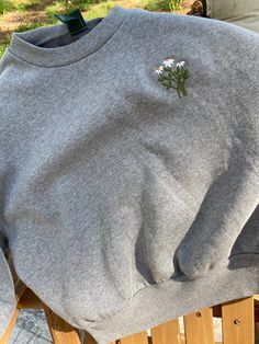 a grey sweatshirt with flowers on it sitting on a wooden bench