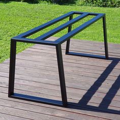 two black metal tables sitting on top of a wooden deck next to green grass and trees