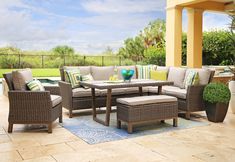 an outdoor patio with furniture and potted plants on the ground near a swimming pool