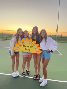 three girls standing on a tennis court holding a sign that says class of 2013 with the sun setting in the background