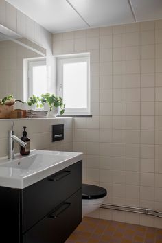 a bathroom with a sink, mirror and toilet in it's corner next to a window