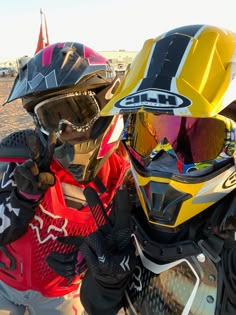 two motorcyclists wearing helmets and goggles on the beach