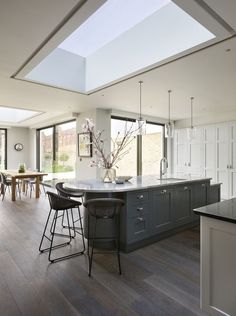 an open kitchen and dining room area with skylights above the countertop, along with bar stools