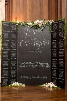 a blackboard sign with white flowers and greenery on it