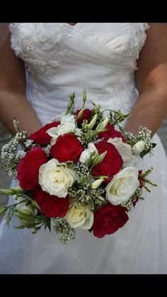 a bride holding a bouquet of red and white flowers