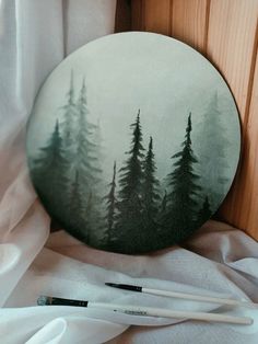 an image of a forest scene painted on a plate with paintbrushes next to it