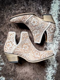 Step into the epitome of Southwestern flair with these Western leather booties, meticulously hand-tooled to highlight a stunning blend of rich white and chocolate hues. Featuring classic cowboy heels and convenient side slits, they blend traditional craftsmanship with modern ease. The intricate design, showcasing a pat Cowboy Heels, Hay Bag, Beautiful Desert, Classic Cowboy, Wrap Boots, Silver Jewelry Box, Horse Boots, Traditional Pattern, Hand Tooled Leather