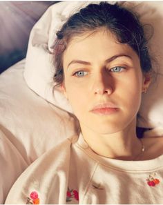 a woman laying in bed with her eyes open and looking at the camera while wearing pajamas