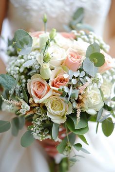 a bridal bouquet with peach and white roses, eucalyptus leaves and baby's breath