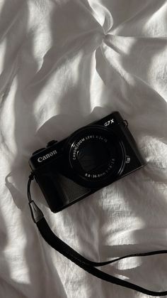 a black camera sitting on top of a white sheet