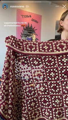 a woman holding up a crocheted blanket in the shape of a cross pattern