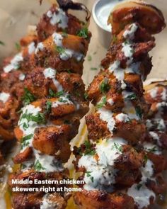 the chicken skewers are covered with white sauce and parmesan cheese on top