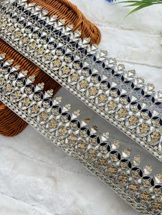 two silver and gold bracelets sitting on top of a white table next to flowers