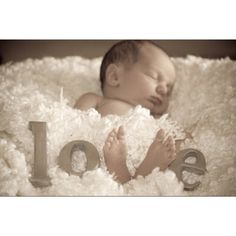 a baby is laying down in a blanket with the word love spelled out next to it