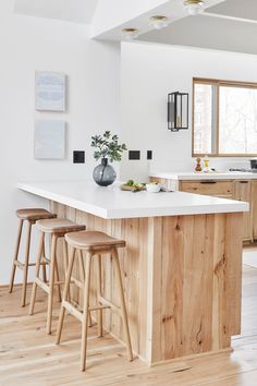 a kitchen island with stools in the middle and an open floor plan behind it