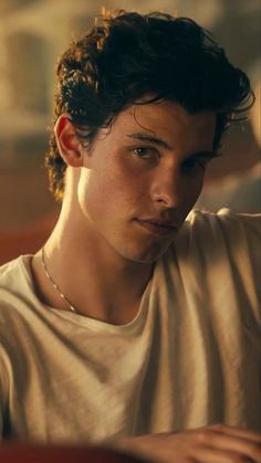 a young man with curly hair is staring at the camera