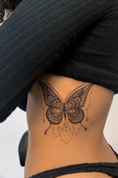 a woman with a butterfly tattoo on her lower back and side ribcage tattoos