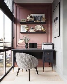 a home office with pink walls and black desk in front of a window overlooking the city