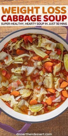 cabbage soup with carrots and other vegetables in a white bowl on top of a wooden table