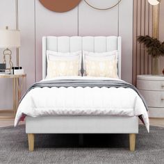 a white bed with two pillows on top of it and a round mirror above the headboard