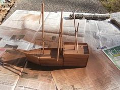 a wooden boat sitting on top of newspaper